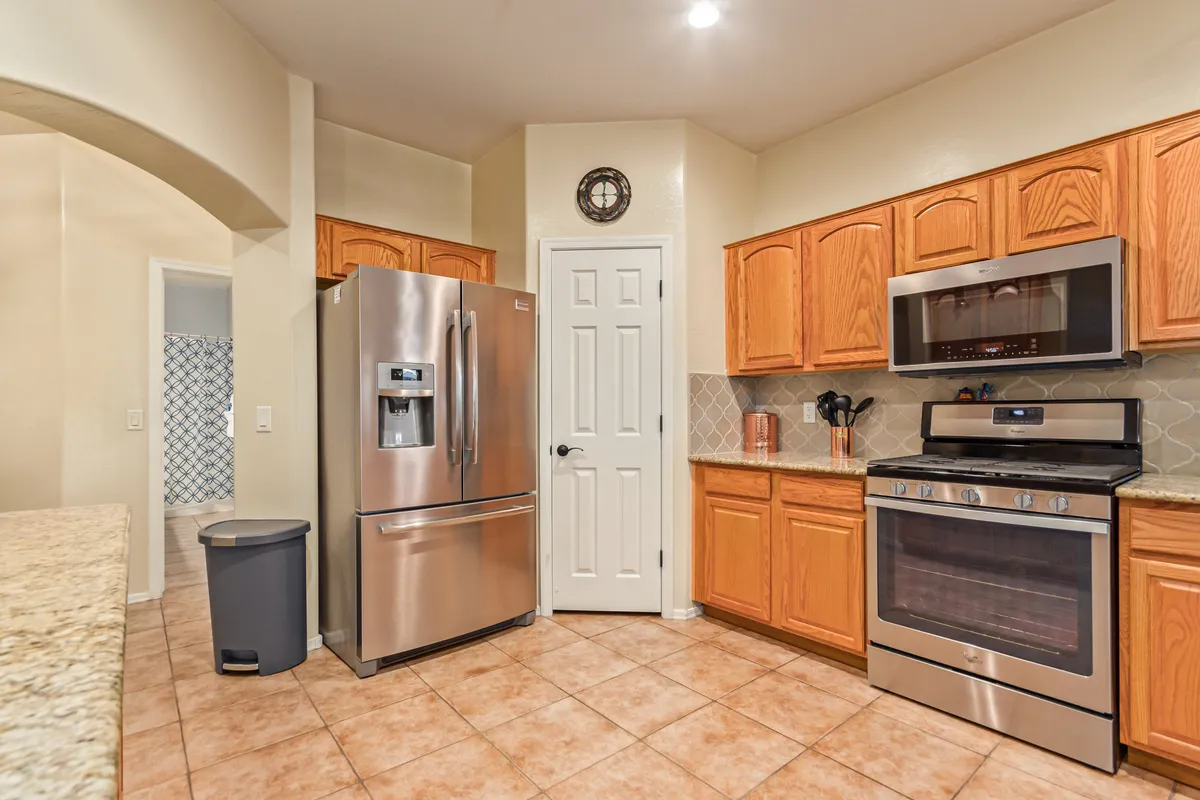 A modern, well-appointed kitchen with stainless steel refrigerator, oven and microwave combination, and granite countertops. The warm lighting and organized layout make it inviting for cooking, entertaining, and gathering.