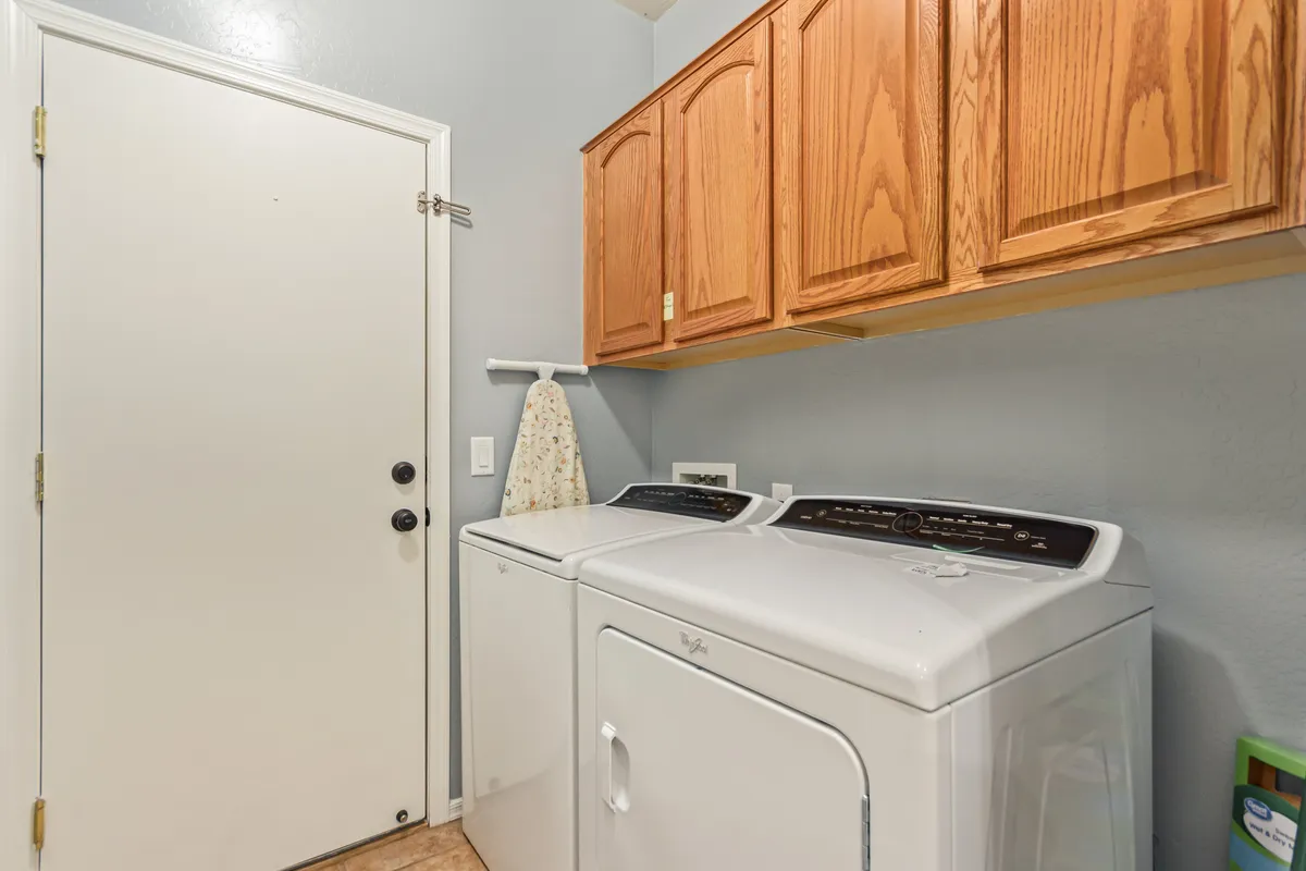 A functional laundry area with a modern washing machine and dryer, set beneath wooden cabinets for storage. The space is bright, organized, and designed for convenience, making household chores effortless during your stay.