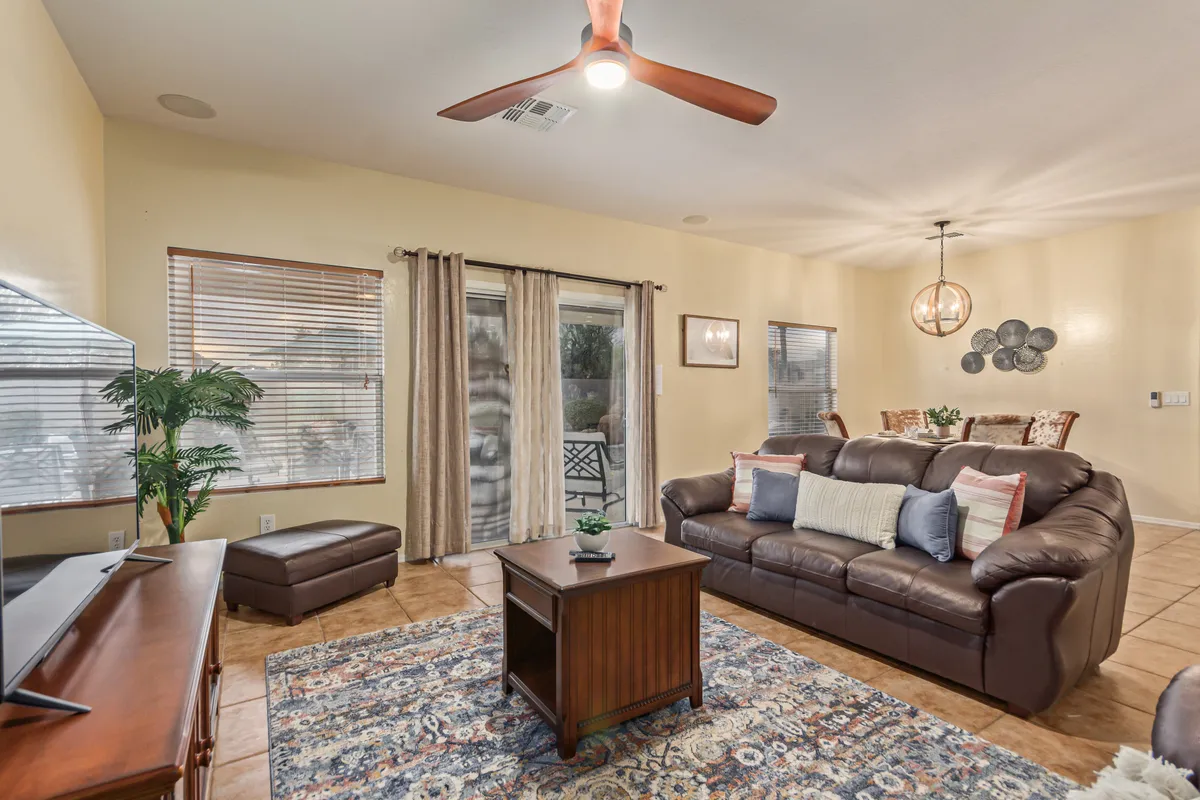 A cozy living area with a plush sofa, contemporary coffee table, and abundant natural light pouring in through a large window. Lush indoor plants and tasteful décor create an inviting atmosphere ideal for unwinding or enjoying a casual gathering.